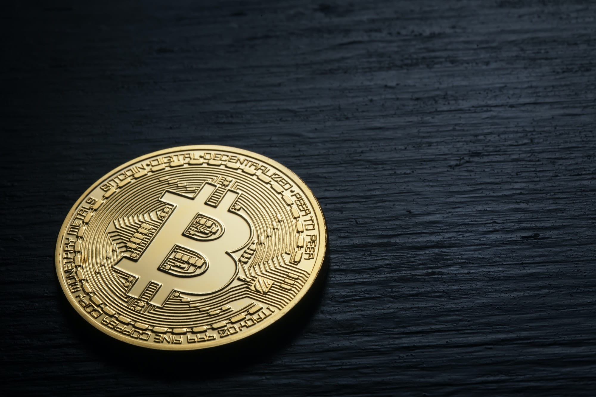 Golden shiny bitcoin on a black wooden background