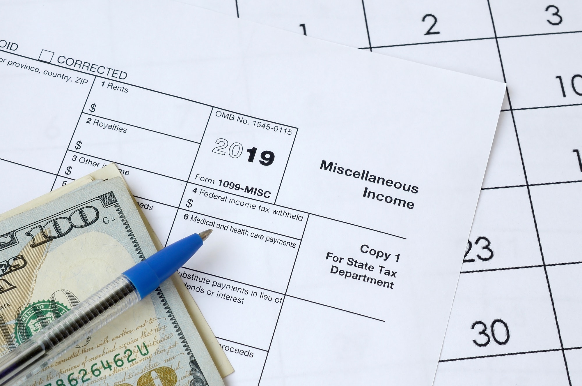 Form 1099-misc Miscellaneous income and blue pen with dollar bills lies on office calendar