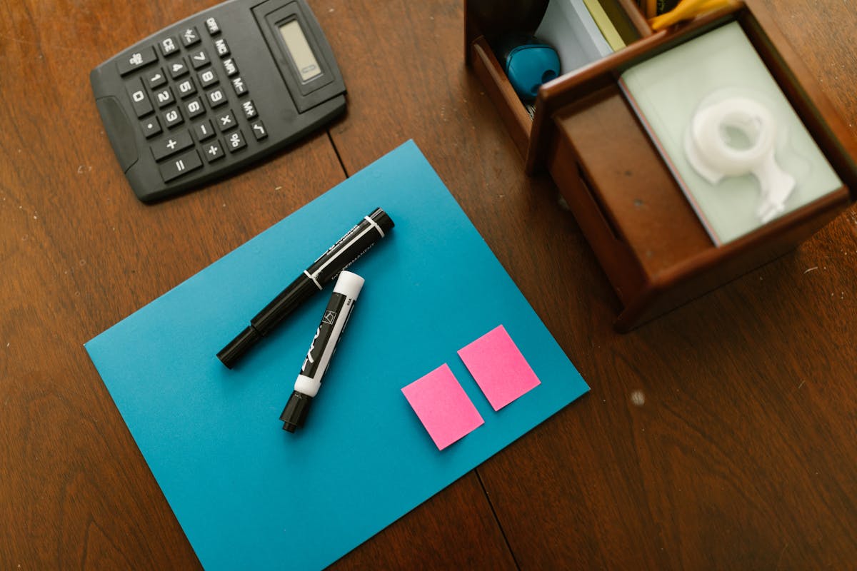 Setting up an AGI calculator using a desk calculator, markers, and notes on a blue folder.