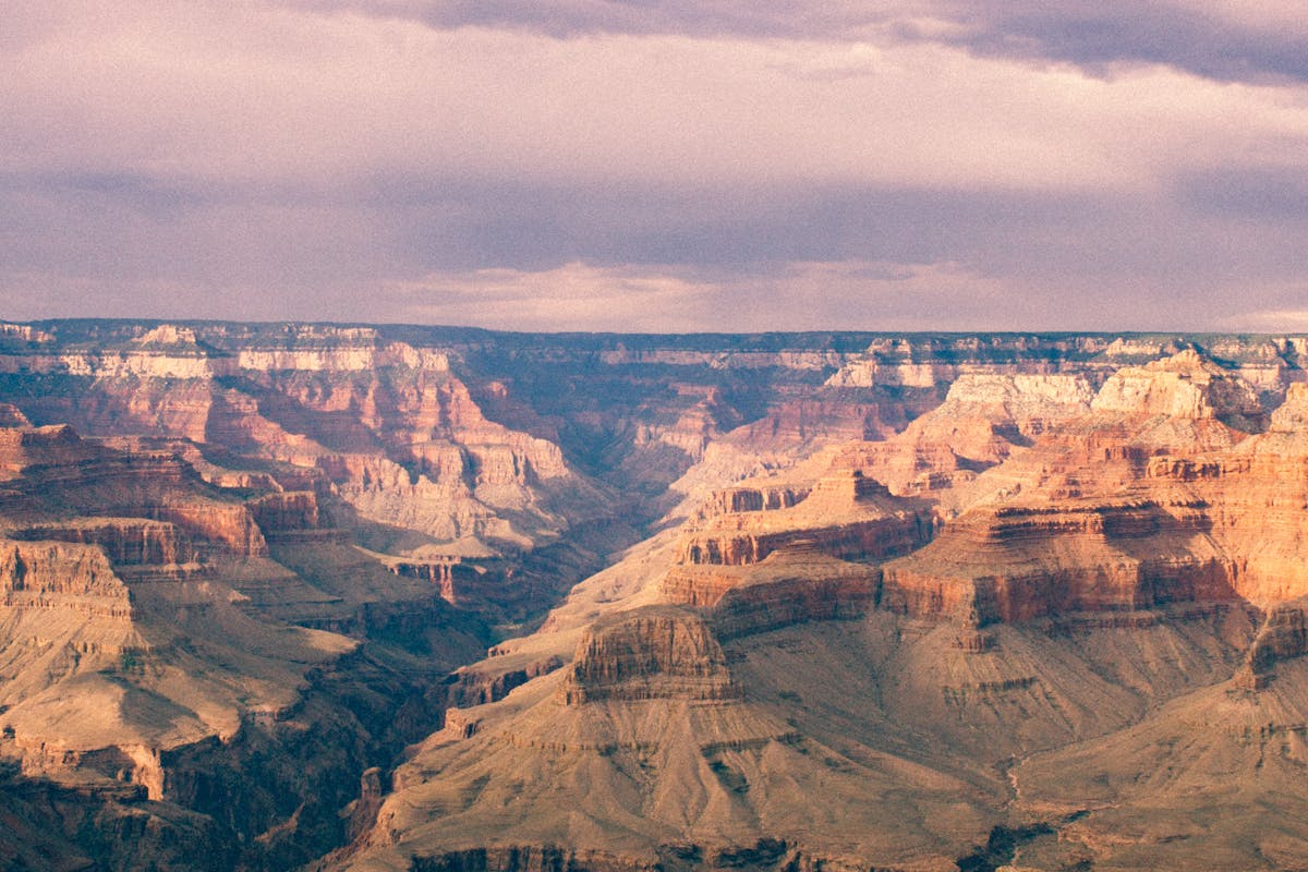 Arizona sales tax represented by a scenic view of the Grand Canyon’s layered red rock cliffs under a cloudy sky.
