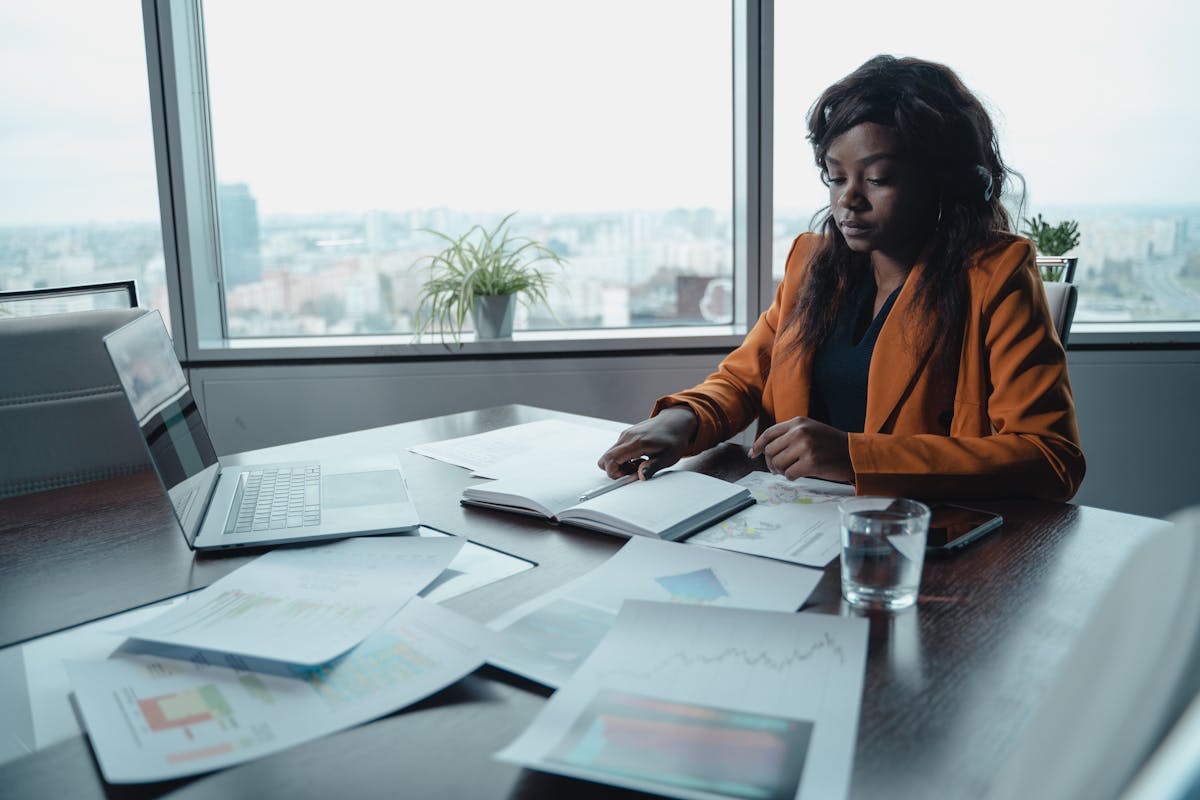 Professional reviewing documents including IRS Form 1040A at an office desk with charts and laptop.