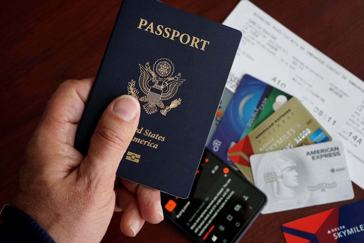 Person holding a U.S. passport next to credit cards, boarding passes, and a phone — concept of expatriation and IRS Form 8854 filing.