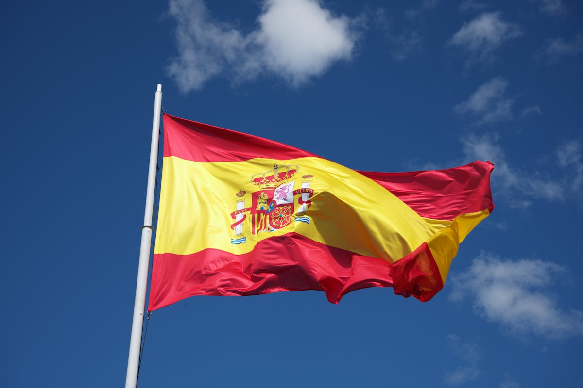 Guide to Retire in Spain as an American shown by Spain’s flag billowing against a bright sky.