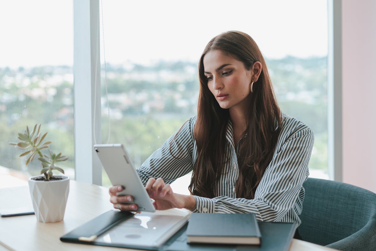 Professional using a tablet to file an annual report at an office desk.