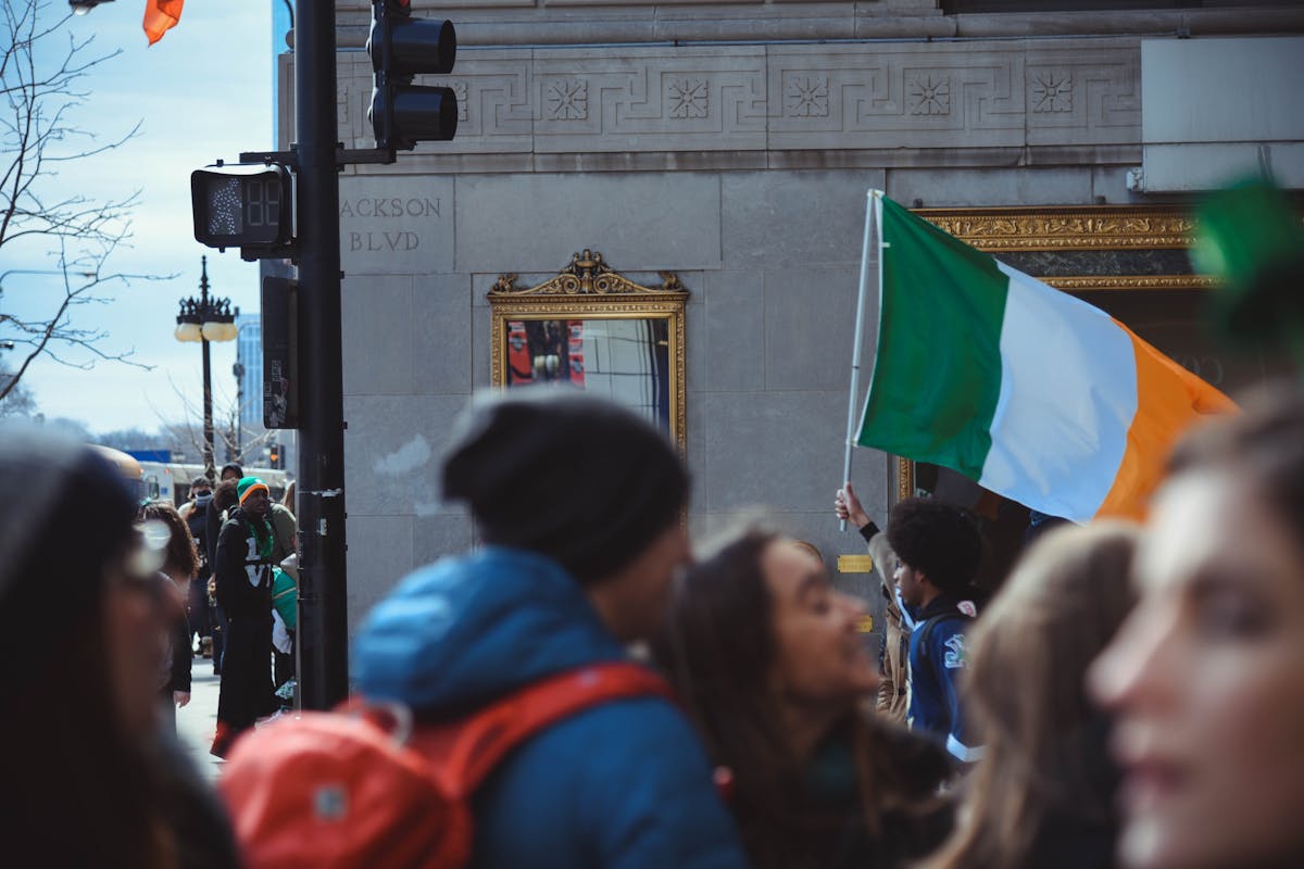 Moving to Ireland from the US shown by a waving Irish flag during an urban gathering.